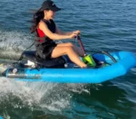 Female rider cruising blue inflatable electric jet kayak on lake waters, motorized water scooter real-use demo